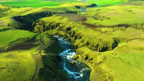 4K-drone,-aerial-cinematic,-unique-and-dramatic-shots-of-a-beautiful-green-landscape-in-Iceland-with-blueish-water-in-the-river-freely-flowing-in-between