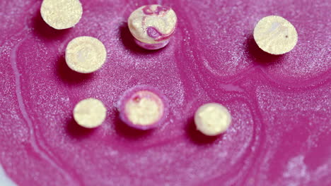 Close-up-of-effervescent-tablets-dissolving-on-pink-surface-with-visible-bubbles-and-texture