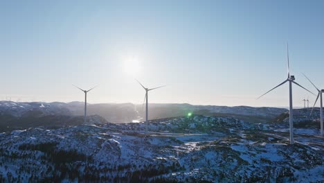 Wind-Turbines-At-Sunrise-Over-Snow-Mountains-Near-Bessaker-Village-In-Norway