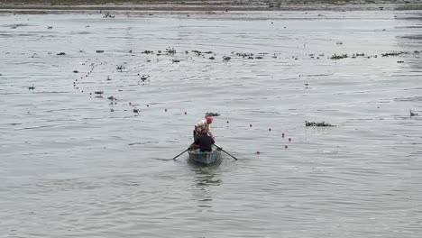 Dos-Pescadores-Recogiendo-Redes-De-Pesca-Del-Mar-Un-Hombre-Remando-El-Viejo-Barco-De-Madera-En-El-Puerto-Usando-Una-Red-De-Plástico-Para-Pescar-Peces-Del-Agua-Ocupación-De-La-Población-Local-En-La-Vida-Urbana-De-La-Ciudad-Portuaria-De-Irán-Anzali