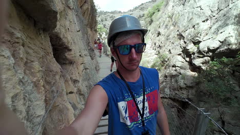 Young-man-walks-alongside-of-cliff-on-a-high-footpath,-filming-himself-in-slow-motion