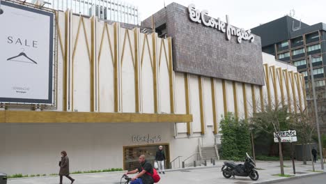 Pedestrians-walk-past-the-Spanish-biggest-department-store-company,-El-Corte-Ingles,-building-in-Spain