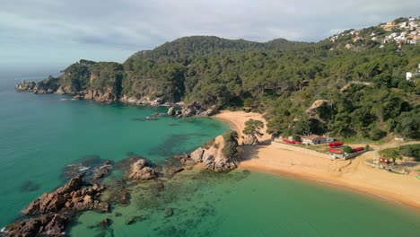 Take-in-the-breathtaking-aerial-images-of-Lloret-De-Mar's-Mediterranean-shore,-highlighting-its-turquoise-waters-and-luxury-tourism-destinations-like-Santa-Cristina-and-Cala-Treumal