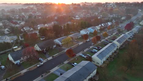 Luftaufnahme-Einer-Vorstadtstraße-Bei-Sonnenaufgang-Mit-Nebel,-Herbstbäumen,-Autos-Und-Verbundenen-Häusern