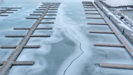 Aerial-shot-of-Port-Elgin-marina-frozen-over-in-winter,-no-boats,-serene-atmosphere,-gray-sky