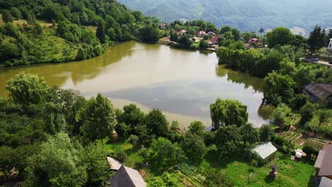 Nucsoara-See-Beim-Dorf-Mit-üppigem-Grün-Und-Malerischen-Häusern,-Tagsüber,-Luftaufnahme