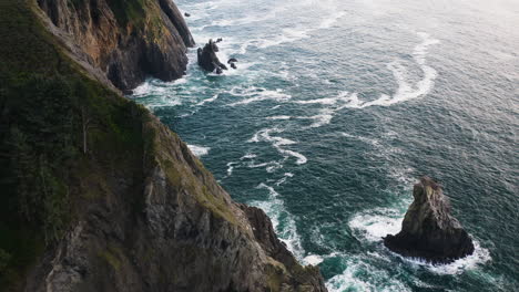 Aerial-view-over-rocky-cliffs-battered-by-turbulent-Pacific-Ocean,-Oregon-Coast