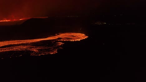 Growing-lava-flow-with-glowing-magma-at-night-in-Iceland,-aerial