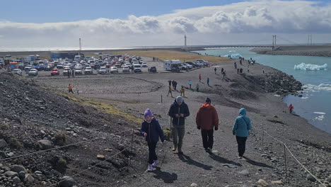 Tourists-Walking-on-Coast-of-Jokulsarlon-Glacial-Lagoon,-Iceland-on-Sunny-Day