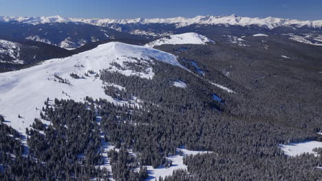Backcountry-Winter-Vail-Pass-Colorado-aerial-drone-i70-Rocky-Mountains-landscape-Ptarmigan-Hill-Mount-of-the-Holy-Cross-sunny-morning-blue-sky-fresh-snow-snowboard-ski-snowmobile-forward-pan-up-reveal