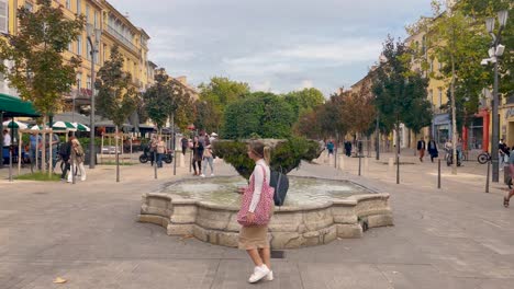Static-shot-of-street-fountain-in-Aix-en-Provence,-France,-crowded-streets-with-people-walking-by-on-public-square