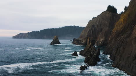 Low-flight-towards-churning-water-of-Pacific-Ocean-into-small-cove,-Oregon-Coast