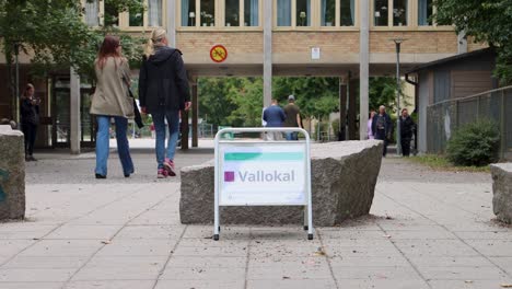 Menschen-Gehen-Am-Wahltag-Am-Wahllokal-Schild-Vorbei,-Stockholm,-Schweden