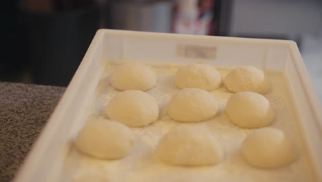 Fresh-pizza-dough-balls-on-tray,-ready-for-baking-in-a-kebab-shop-kitchen,-focus-on-foreground