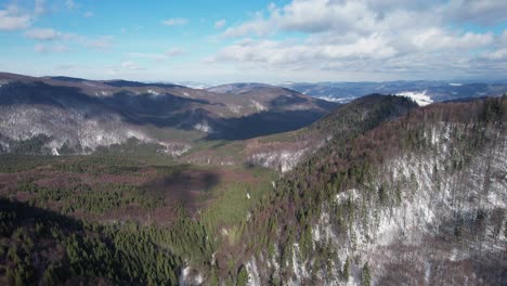 Siriu-Berge-Mit-Schneebedeckten-Flecken-Und-üppigen-Wäldern-Unter-Blauem-Himmel,-Luftaufnahme