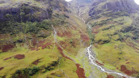 Luftaufnahme-Der-Malerischen-Glencoe-Berglandschaft-Mit-Herabfließendem-Fluss
