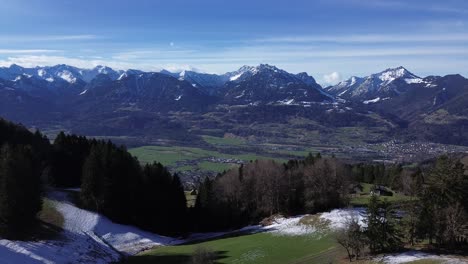 Drohnenaufnahme-Einer-Winterlichen-Berglandschaft-Mit-Schneebedeckten-Bergen-Und-Stadtbild