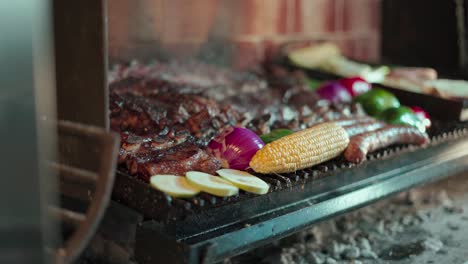 moving-shot-of-a-smoking-grill-full-of-freshly-grilled-meat-and-vegetables-from-which-a-person-helps-himself-to-a-portion-of-meat