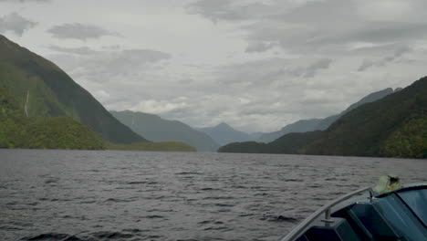 Slow-Motion-pan-up-from-the-bow-of-a-boat-looking-out-into-Doubtful-Sound-fjord-with-mountains-and-water---Patea,-New-Zealand