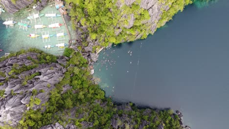 Jagged-sharp-rock-ridge-separating-Barracuda-freshwater-Lake-from-ocean-in-Coron-island-Philippines,-aerial-rising-top-down