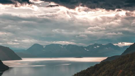 Nubes-Tormentosas-Iluminadas-Por-El-Sol-Poniente-Giran-Sobre-El-Tranquilo-Fiordo-Y-Las-Montañas-En-El-Vídeo-Timelapse