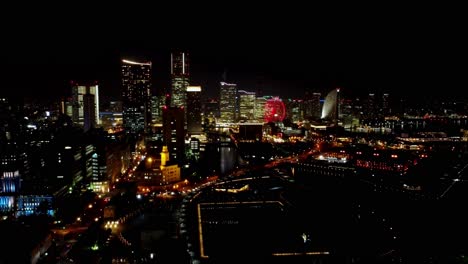 Vista-Nocturna-De-Una-Bulliciosa-Ciudad-Con-Edificios-Iluminados-Y-Una-Noria