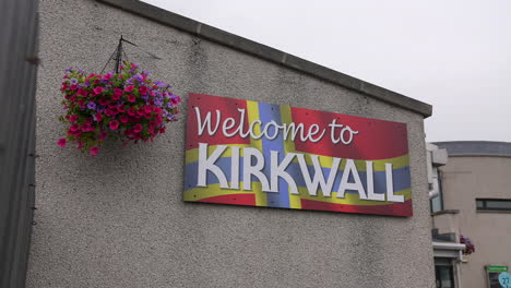Welcome-to-Kirkwall-Sign-With-Orkney-Flag-on-House-Facade,-Scotland-UK
