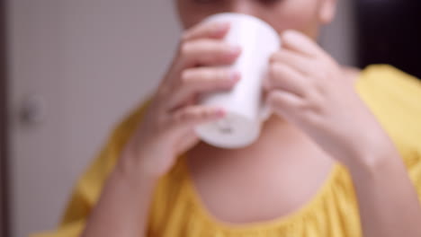 Close-up-of-a-woman-who-is-wearing-a-yellow-dress-is-holding-a-mug-while-sipping-and-drinking-some-coffee