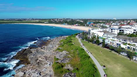 Drone-aerial-landscape-pan-Maroubra-beach-people-on-walkway-pathway-street-residential-housing-activities-headland-coast-Sydney-travel-tourism-Australia