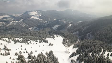 Snow-covered-mountains-under-a-soft-cloudy-sky,-aerial-shot-conveying-calm-winter-landscape