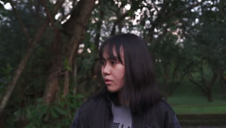Distressed-Asian-teenage-girl-looks-around-dark-forest-in-worry-and-panic