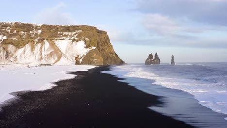 4K-drone,-aerial-cinematic-shots-of-the-Dramatic-scenery-of-Gerouberg-cliff,-and-the-Nordic-Sea,-with-the-waves-crashing-towards-the-shore-trying-to-reach-out-towards-the-white-snowscape