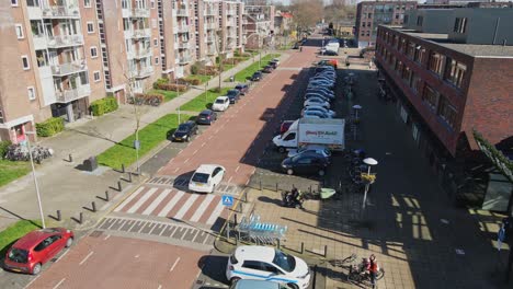 Drone-following-white-car-driving-over-street-and-passing-a-cyclist