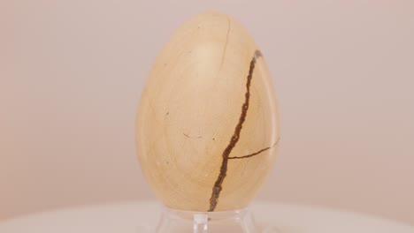 Wooden-egg-rotating-on-a-turn-table-in-front-of-a-white-background