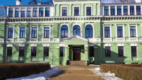 Reveal-backwards-dolly-of-Kokmuiža-Manor-Complex,-beautiful-green-villa-in-Latvia-with-Latvian-flag-atop