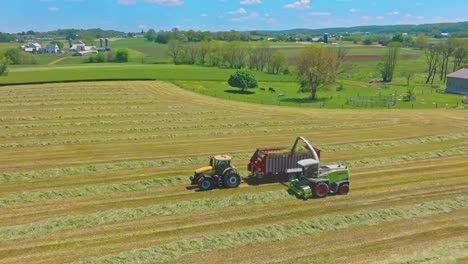 Ein-Claas-Traktoren-Arbeiten-In-Harmonie,-Pressen-Heu,-Wenn-Der-Tag-Zu-Ende-Geht,-Und-Verwandeln-Felder-In-Ordentlich-Organisierte-Linien-Unter-Azurblauem-Himmel