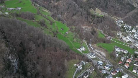 Descripción-General-A-Vista-De-Pájaro-Sobre-Casas-Europeas-En-Laderas-Cubiertas-De-Hierba-En-Walensee,-Suiza