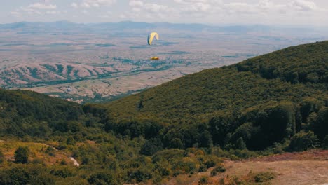 Paragliding-expert-gliding-peacefully-through-the-air-above-a-forest