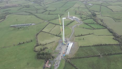 Toma-Aérea-De-La-Construcción-De-Turbinas-Eólicas-En-La-Zona-Rural-De-Monaghan,-Irlanda,-Con-Exuberantes-Campos-Verdes.