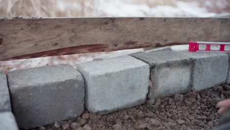 El-Hombre-Está-Usando-Un-Nivel-Para-Asegurarse-De-Que-El-Bloque-De-Concreto-Esté-Correctamente-Alineado-Debajo-Del-Jacuzzi-De-Bricolaje---De-Cerca