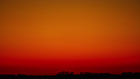 Helle-Linie-Der-Flugzeugspur-Im-Roten-Himmel-Unter-Einem-Dunklen-Horizont