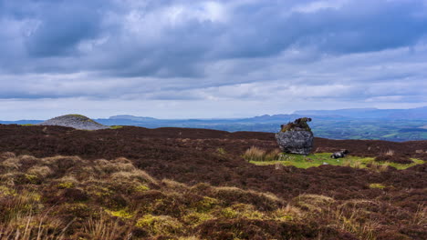 Timelapse-of-rural-nature-farmland-with-sheep-nearby-a-passage-tomb-and-ancient-rock-boulder-in-a-bog-field-during-sunny-cloudy-day-viewed-from-Carrowkeel-in-county-Sligo-in-Ireland