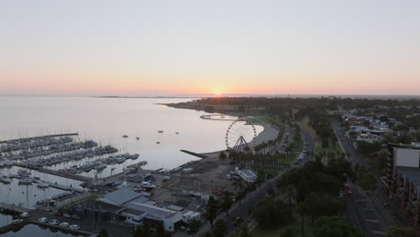 AERIAL-Sun-Rises-Over-Geelong,-Australia-Eastern-Beach-With-Ferris-Wheel
