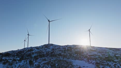 Windmills-For-Electricity-Production-On-Snowy-Mountain-In-Bessaker,-Norway---Drone-Shot