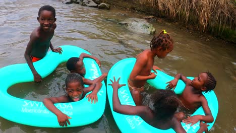 A-group-of-happy-African-children-enjoying-playing-on-floats-on-a-river-in-São-Tomé,Africa