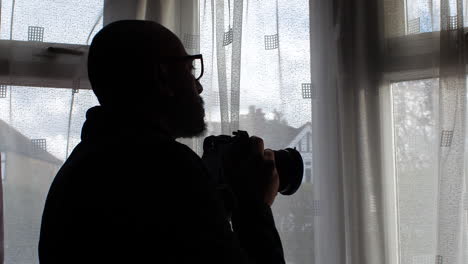 Man-Taking-Picture-With-Camera-Out-Of-Window-At-Home---Close-Up