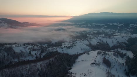Sunrise-over-Pestera-Village-with-mist,-winter-landscape,-aerial-view