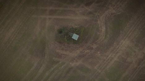 Toma-De-Drone-De-Un-Puesto-De-Ciervos-En-Medio-De-Un-Campo-Con-Senderos-De-Tractor-Visibles