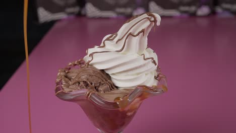 Pouring-caramel-over-ice-cream-dessert-with-chocolate-side-view