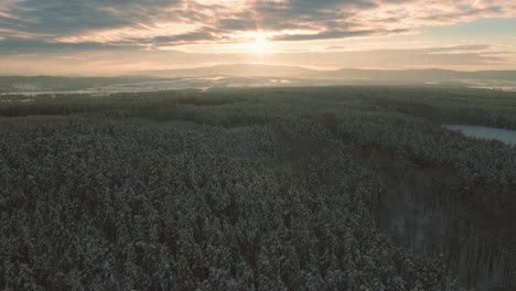 Dramatic-and-epic-drone-shot-of-the-woods-and-fields-with-mountains-in-the-background-bird-view,-during-a-sunset-or-a-sunrise-dusk-or-dawn
